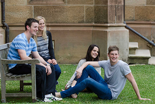 Male and female residents socialising together on a bench outside the Main Building overlooking The Glen.